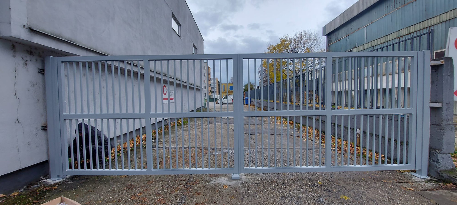 Sivá vstupná brána s lamelovou výplňou pri objekte